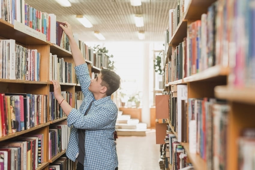 a boy getting a book from a shelf